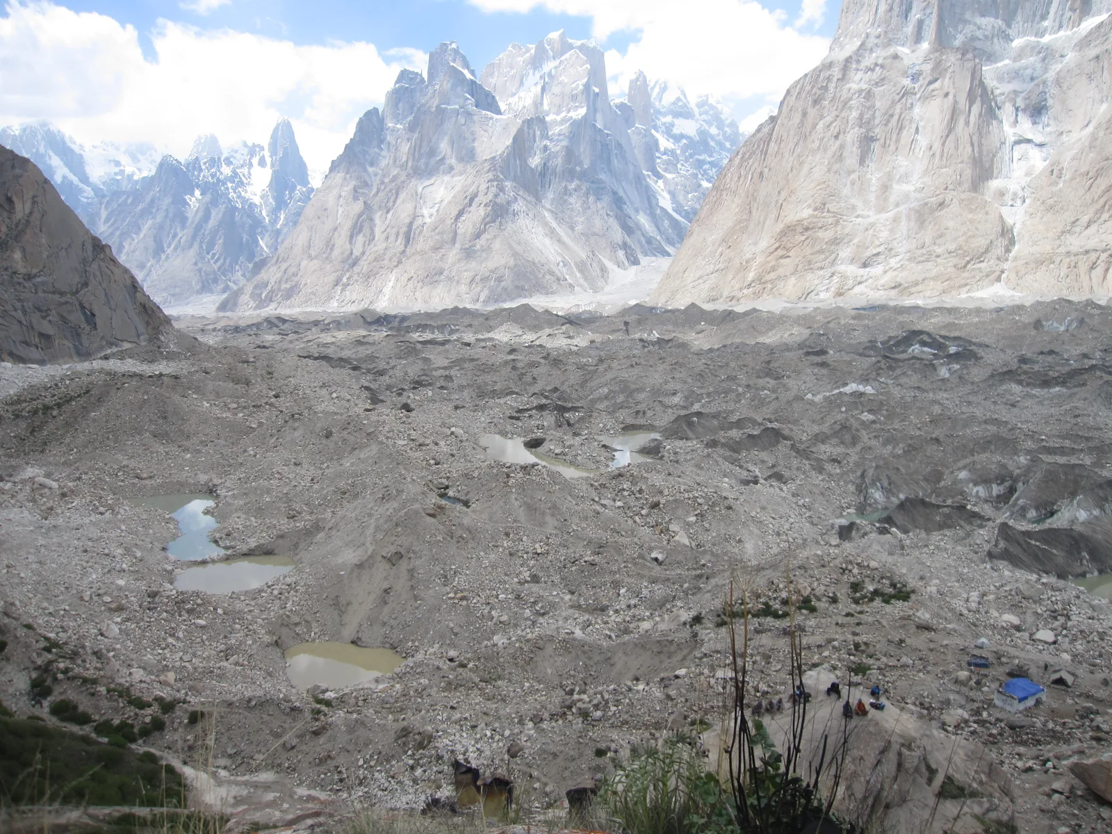 Blick über den Baltoro-Gletscher vom grasigen Lagerplatz Urdukas, mit Granittürmen des Karakorum dahinter