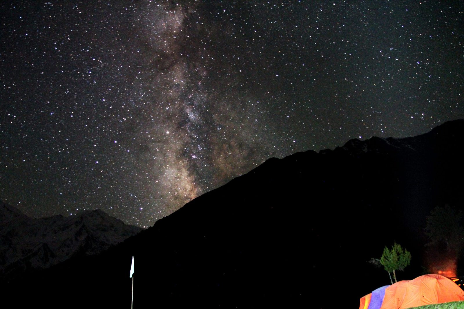 Milchstraße und Sterne über den Holzhütten und dem Zeltplatz von Fairy Meadows bei Nacht