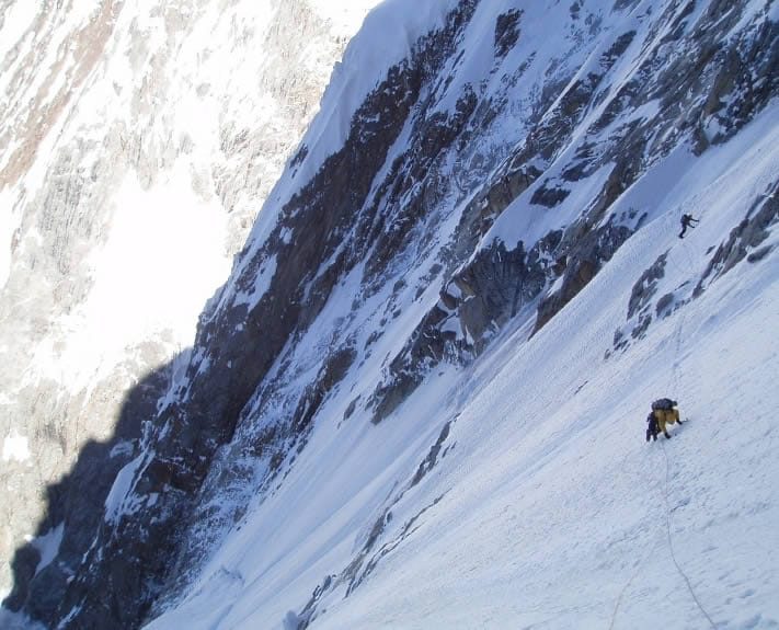 Climber traversing a snow ledge on the southwest face of Khunyang Chhish East